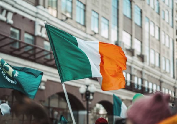 National Flag of Ireland close-up above people crowd, city street, traditional carnival of St. Patrick's Day